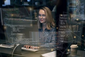 Seorang wanit bule berkacamata yang tengah mengerjakan programming